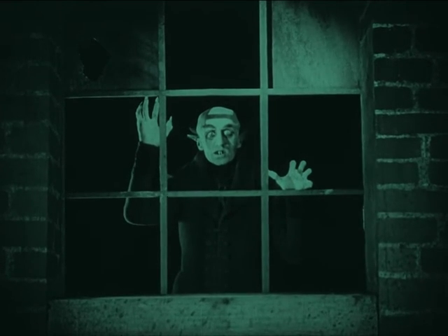 Max Schreck as Count Orlok at a window in Nosferatu (1922), retaining the source excerpt’s green tint